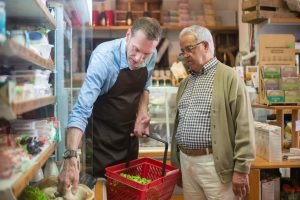 A business owner holding a basket for a customer and helping him select produce - Twelve and a Half Emotional Ingredients Necessary for Business Success