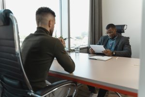 Two men at an office table where one is reviewing and giving feedback to the other.